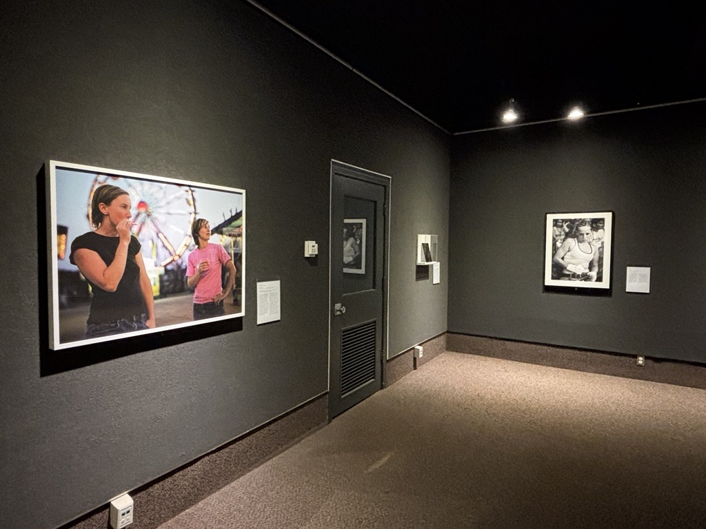 Art gallery with framed photographs on dark walls under spotlights.