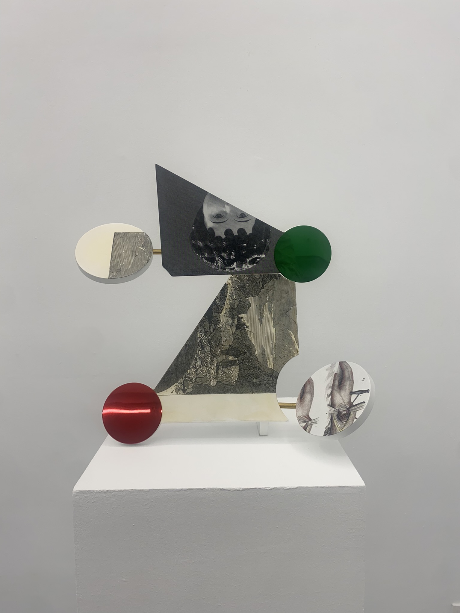Abstract sculpture with geometric shapes, grayscale images, and red and green circular accents.