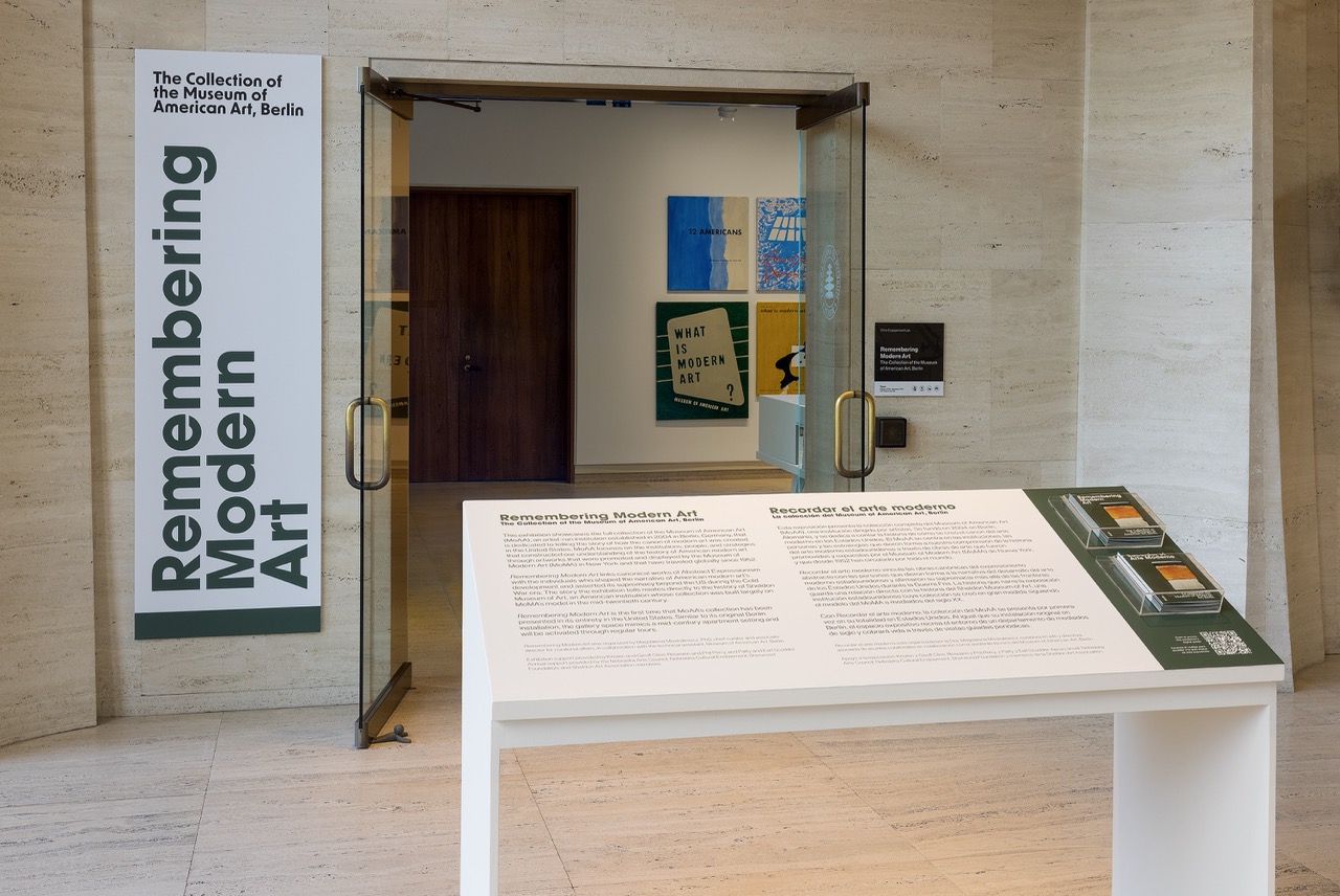 Glass doors lead to an art exhibit, with text panels and colorful paintings visible inside.