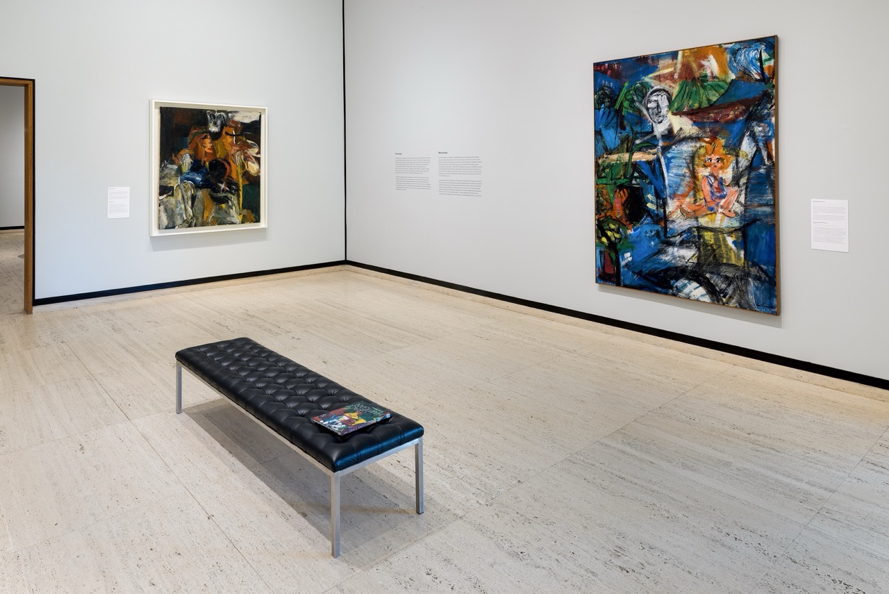 Art gallery room with two colorful paintings on the walls and a black bench in the center.