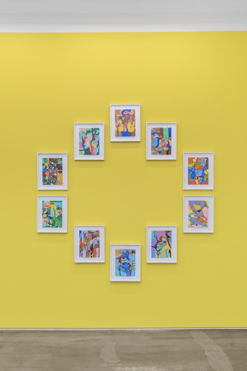 Framed colorful artworks arranged in a circular pattern on a bright yellow wall.