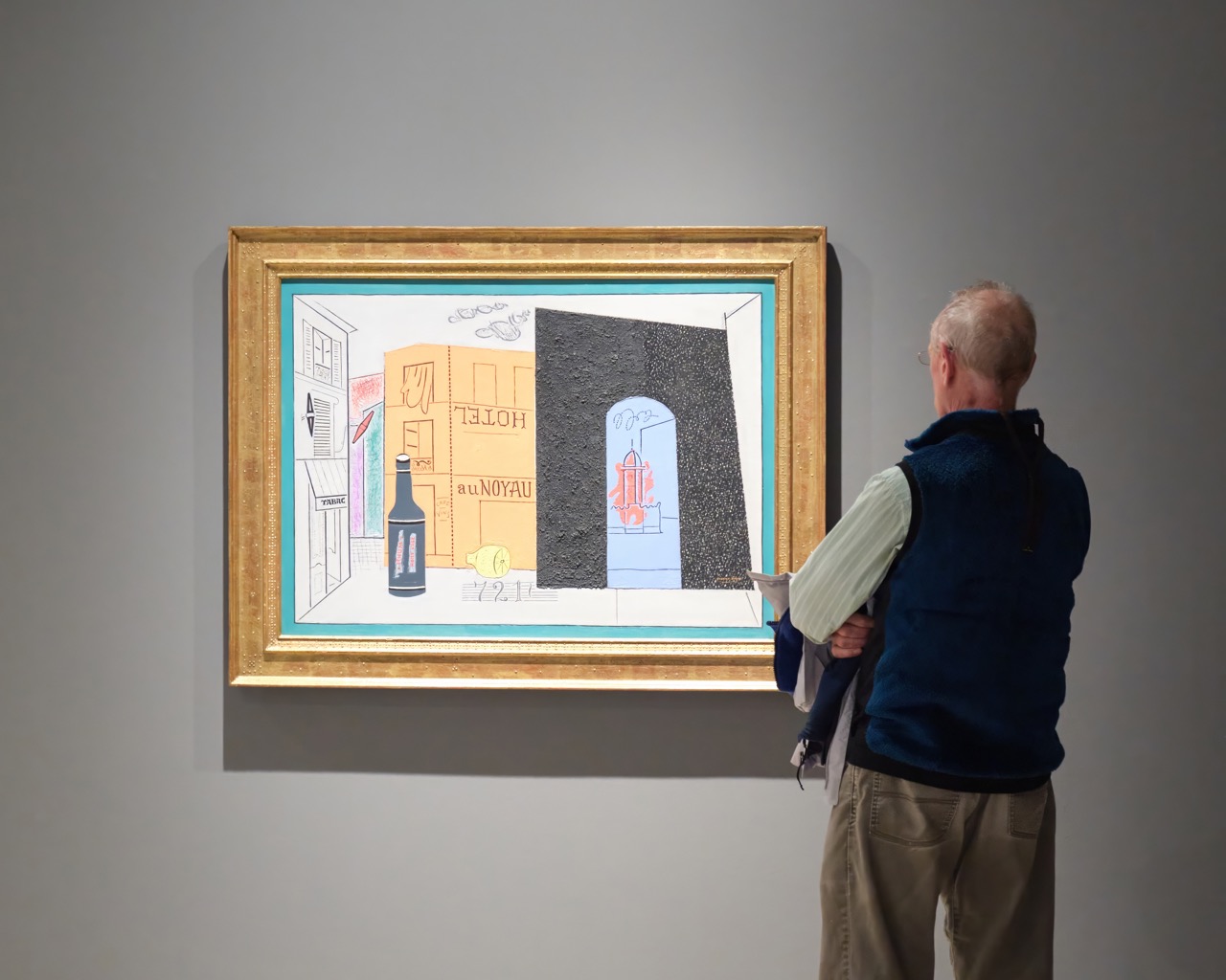 Man observing colorful framed painting in a gallery.