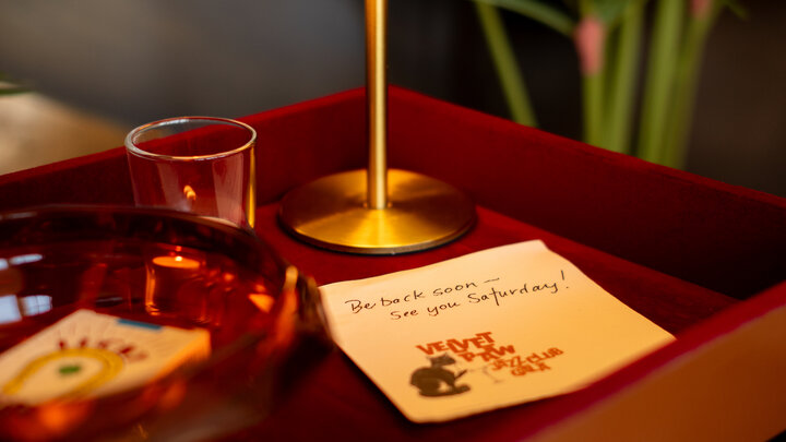 Red tray with a lamp, glass, bowl, and paper card featuring text and illustrations.