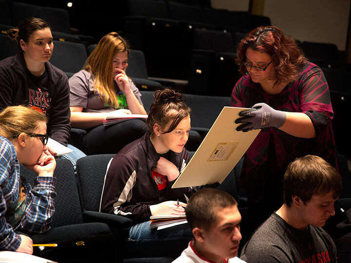Genevieve Ellerbee examines collection prints with visiting UNL students